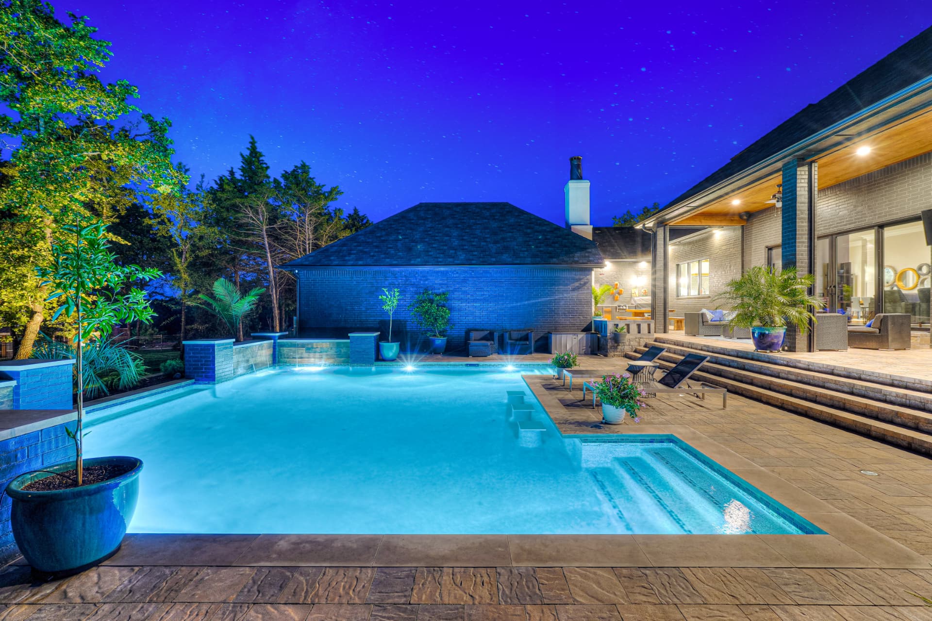 Evening view of the pool, spa and lit outdoor living space