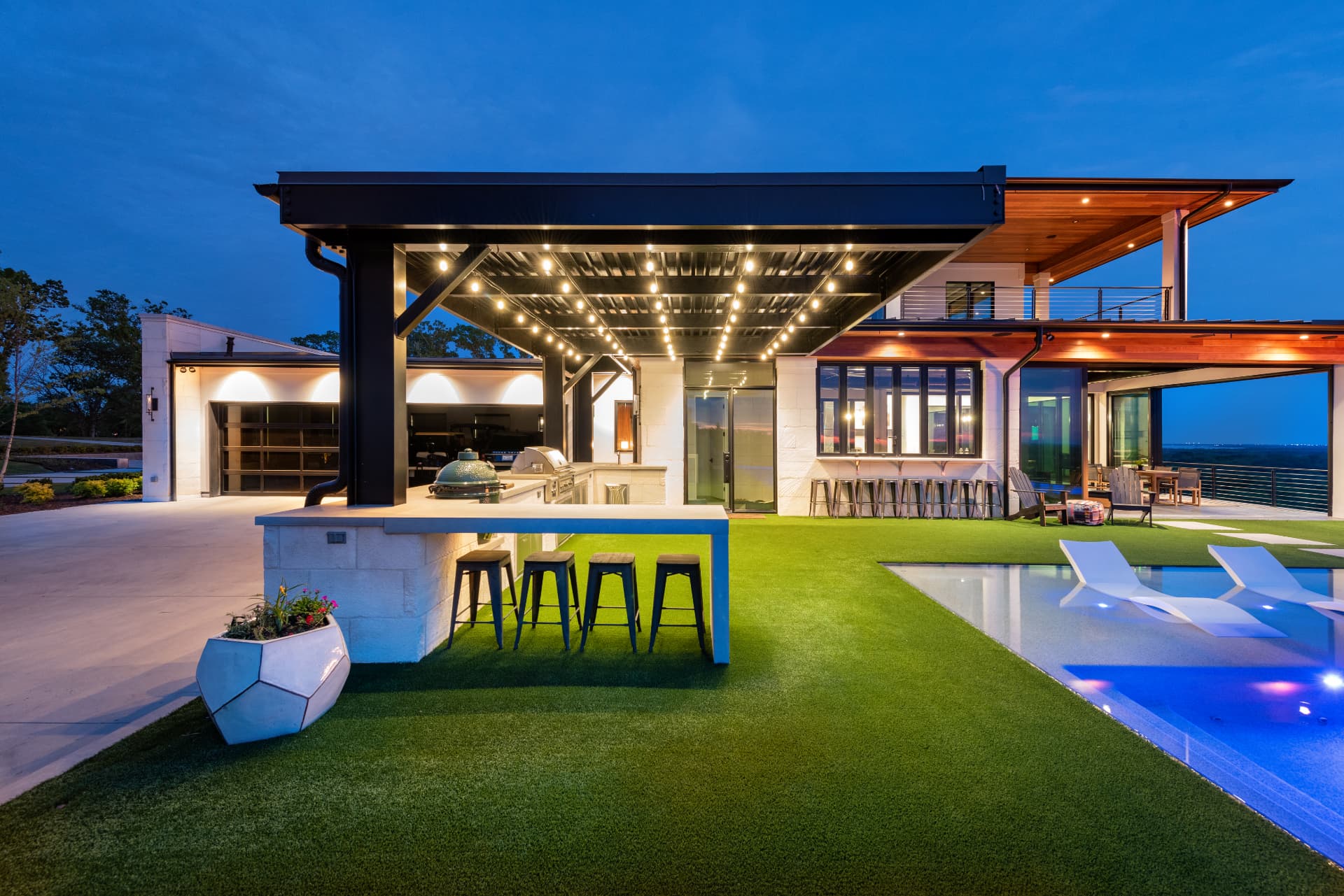 Covered outdoor kitchen and bar illuminated at twilight