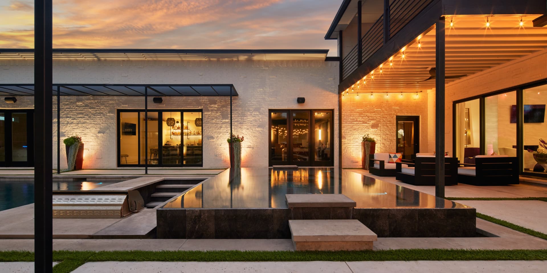Modern courtyard pool with string lights at sunset