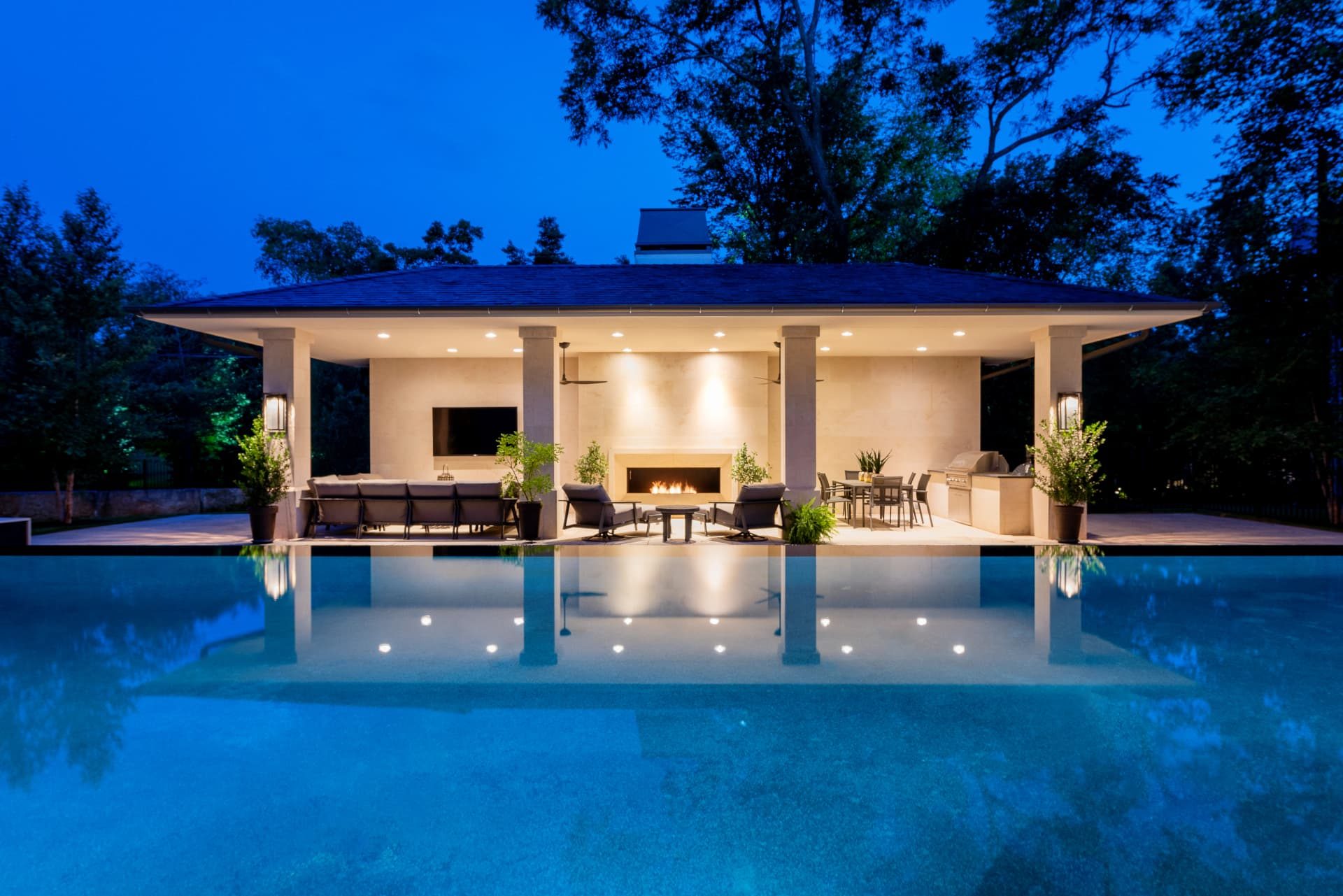 Cabana with fireplace reflected in the still pool water