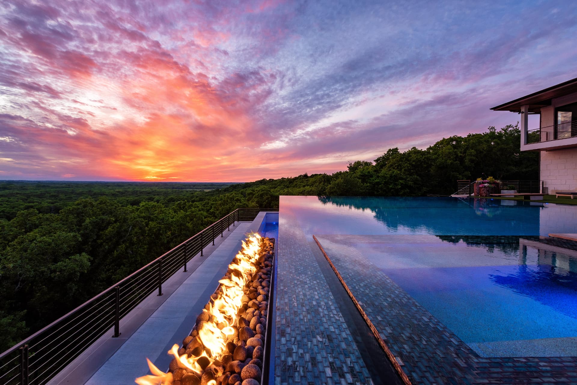 Linear fire feature alongside the glass tile spillway at dusk