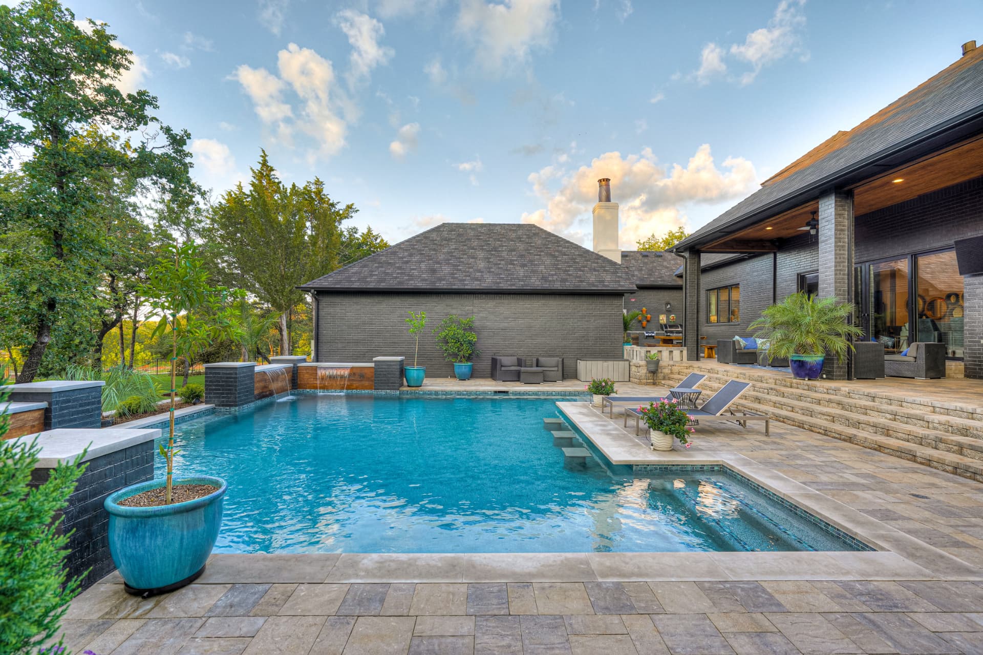 Pool and covered patio looking back toward the black brick home
