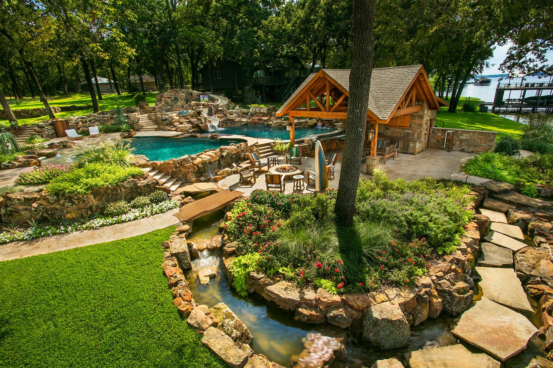 Overview of the Cedar Creek Lake resort backyard with pools, cabana and river