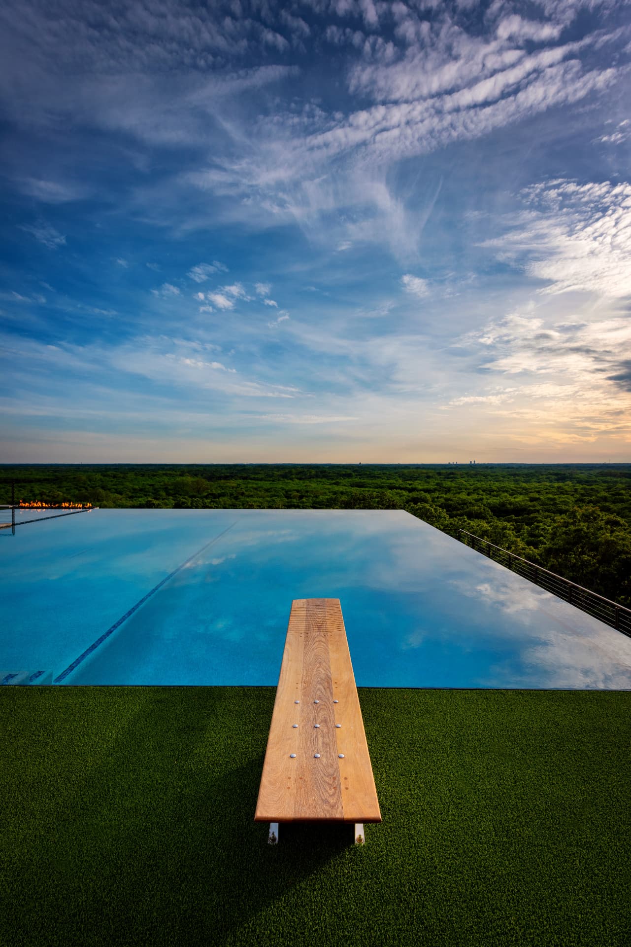 Wooden diving board looking out over the pool and treetops
